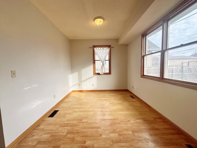 spare room with a textured ceiling and light wood-type flooring