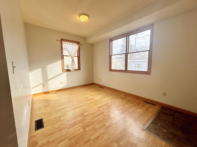 spare room featuring a textured ceiling and light wood-type flooring