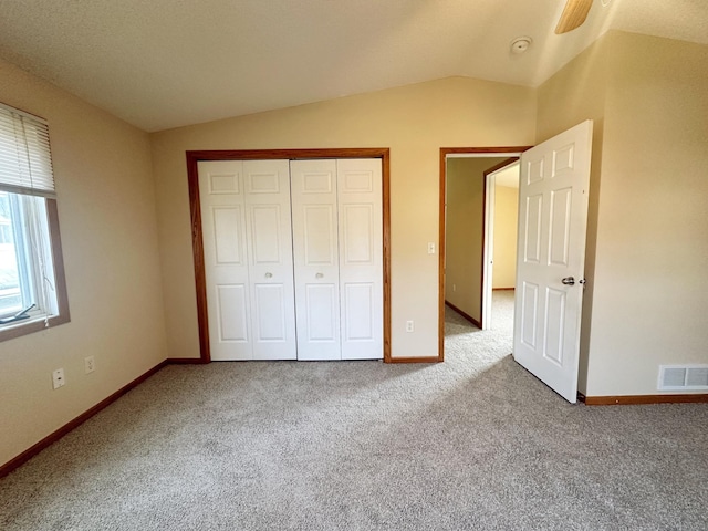 unfurnished bedroom featuring carpet floors, vaulted ceiling, and a closet