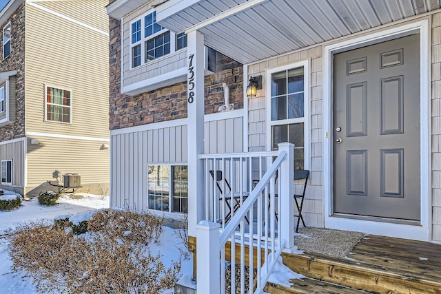 snow covered property entrance with central AC unit