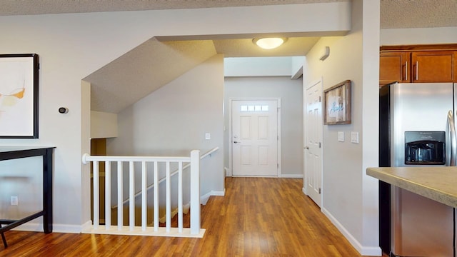 hall with baseboards, an upstairs landing, a textured ceiling, and wood finished floors