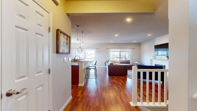 corridor featuring recessed lighting, wood finished floors, baseboards, and a textured ceiling