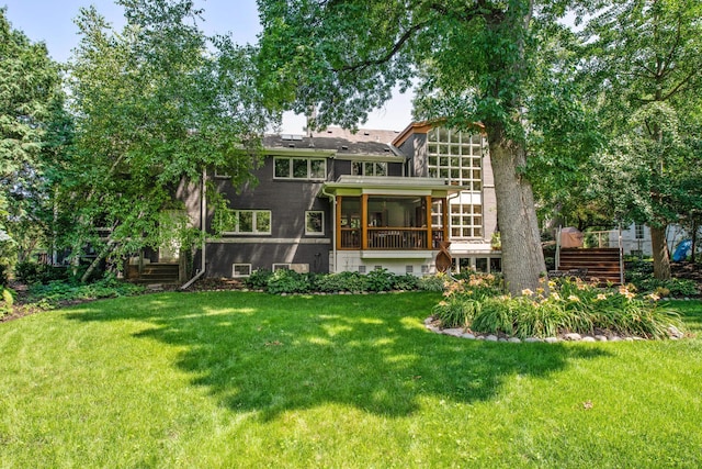 back of house featuring a lawn and a sunroom