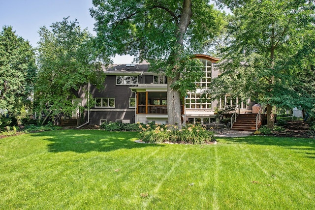 rear view of property featuring a yard and a sunroom