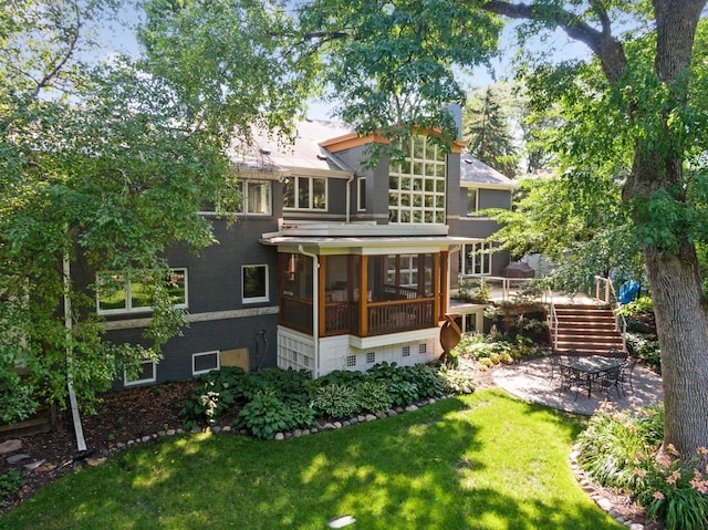 back of house featuring a yard, a patio, and a sunroom