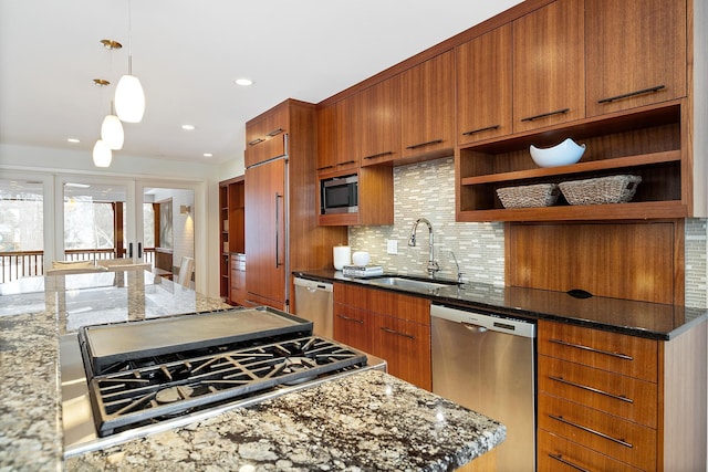 kitchen featuring sink, dark stone countertops, hanging light fixtures, built in appliances, and tasteful backsplash