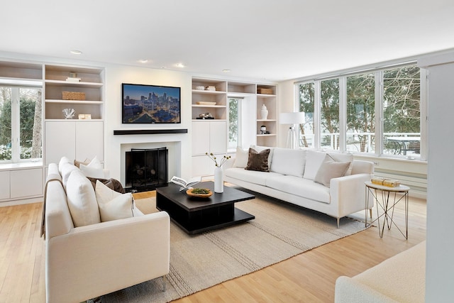 living room featuring built in features and light hardwood / wood-style flooring