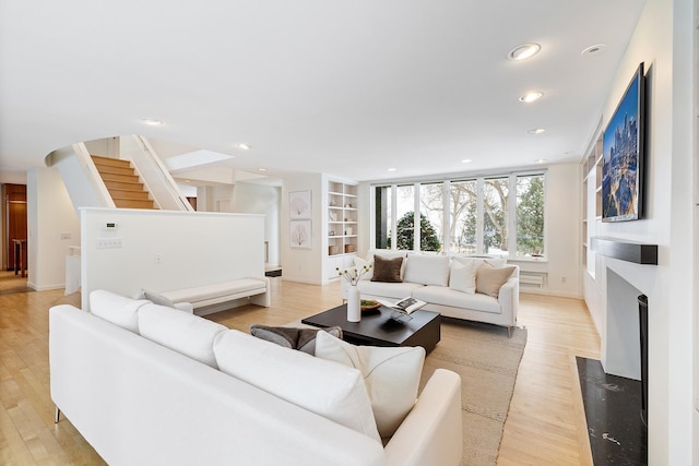 living room featuring built in features and light hardwood / wood-style flooring