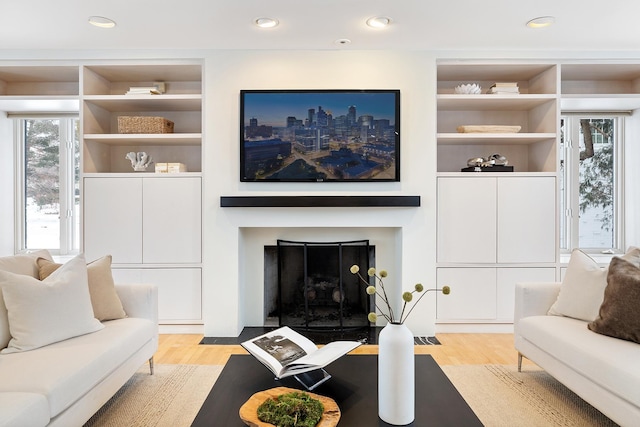 living room featuring built in shelves and light hardwood / wood-style flooring