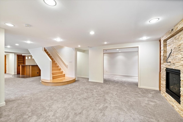 basement featuring a stone fireplace and carpet