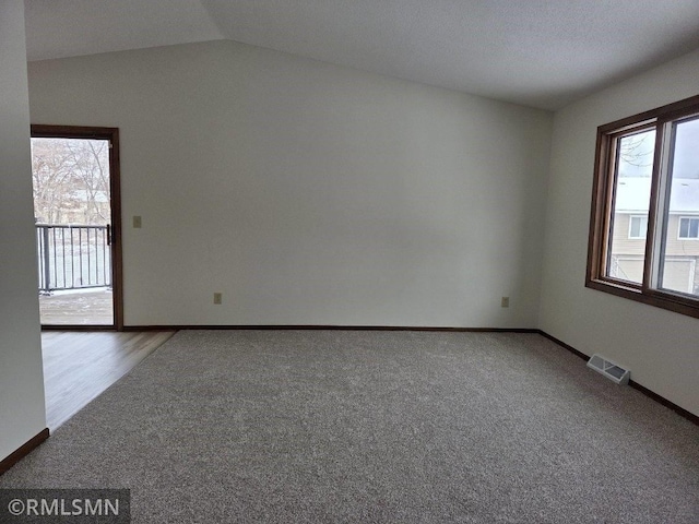 carpeted empty room with lofted ceiling