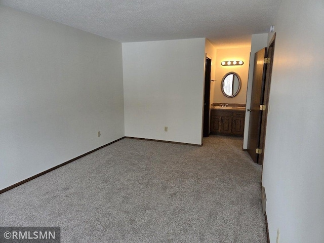 spare room featuring light colored carpet, sink, and a textured ceiling