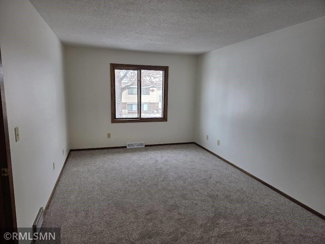 carpeted empty room featuring a textured ceiling