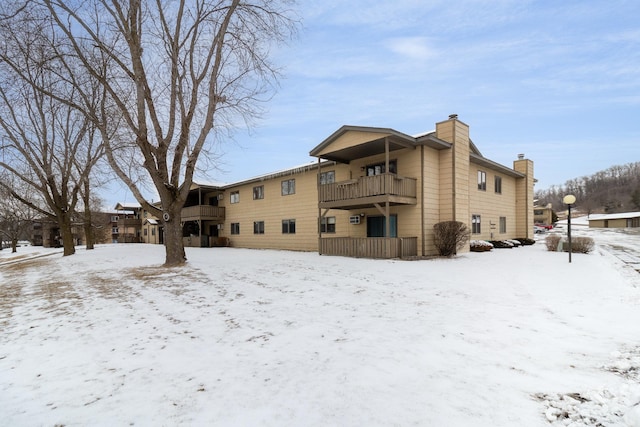 snow covered back of property with a balcony