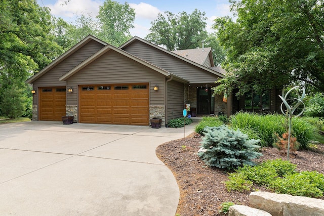 view of front of property featuring driveway, stone siding, and an attached garage