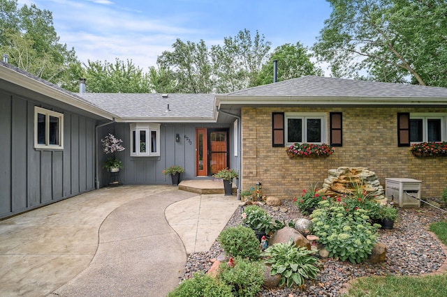 ranch-style house featuring brick siding, board and batten siding, and a shingled roof