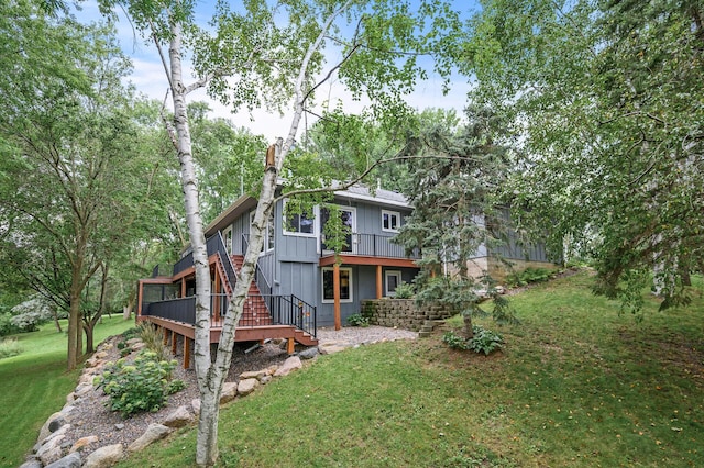 back of property featuring stairway, a wooden deck, and a yard