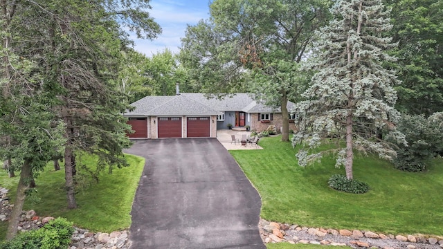 single story home featuring aphalt driveway, a front lawn, a garage, and brick siding