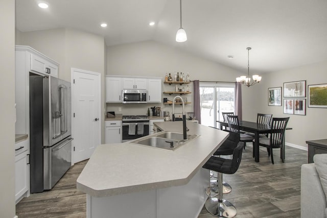 kitchen with sink, appliances with stainless steel finishes, white cabinetry, hanging light fixtures, and a center island with sink