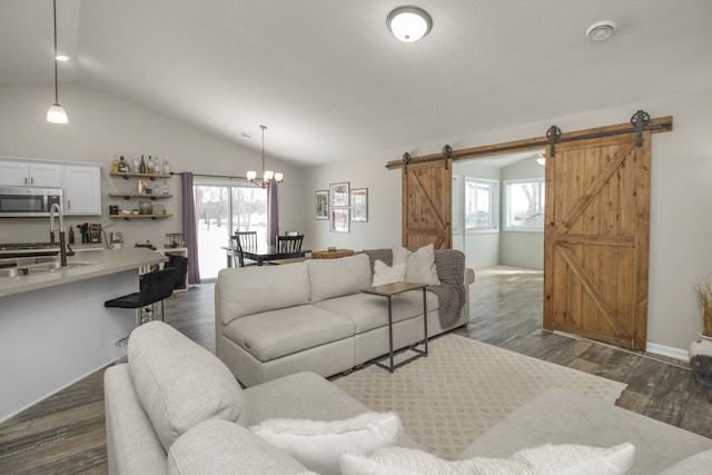 living room featuring lofted ceiling, sink, a barn door, and a healthy amount of sunlight