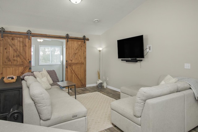 living room with vaulted ceiling, a barn door, and wood-type flooring