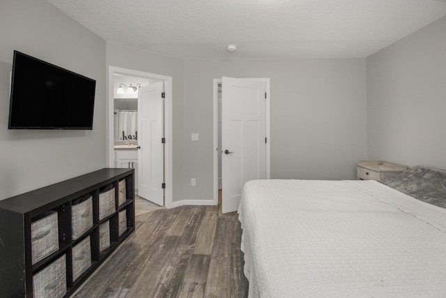 bedroom featuring hardwood / wood-style flooring, ensuite bath, and a textured ceiling