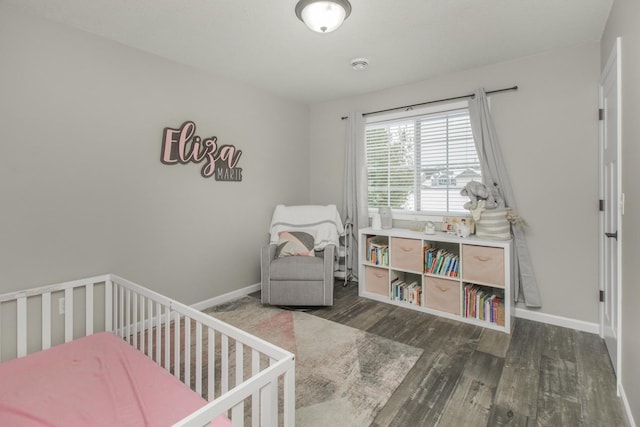 bedroom with dark hardwood / wood-style flooring and a crib