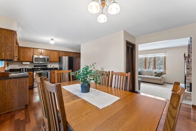 dining space featuring sink, an inviting chandelier, a textured ceiling, and dark hardwood / wood-style floors