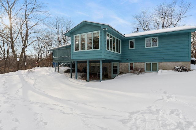 snow covered back of property featuring a deck