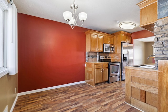 kitchen with tasteful backsplash, a sink, baseboards, stainless steel appliances, and dark wood-style flooring