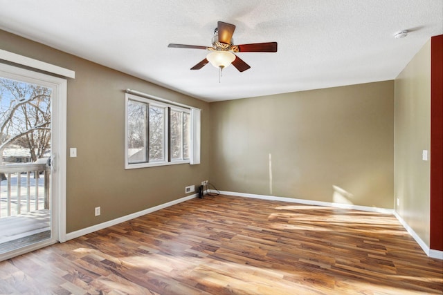 spare room featuring plenty of natural light, baseboards, a ceiling fan, and wood finished floors