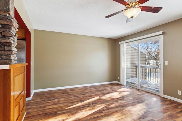 interior space featuring a ceiling fan, wood finished floors, baseboards, and a textured ceiling