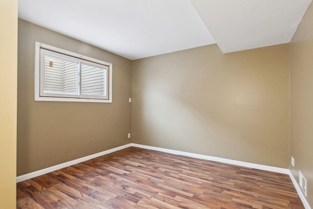 unfurnished room featuring visible vents, baseboards, and wood finished floors