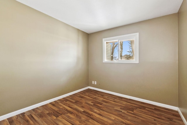 spare room featuring dark wood-type flooring and baseboards