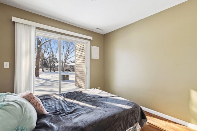 bedroom featuring access to exterior, visible vents, baseboards, and wood finished floors