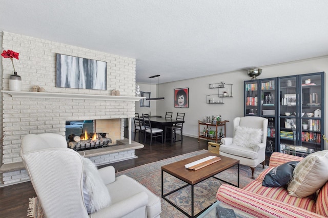 living room featuring dark hardwood / wood-style flooring, a brick fireplace, and a textured ceiling