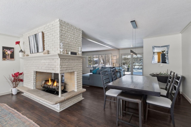 dining room featuring dark wood-type flooring, ornamental molding, a brick fireplace, and a textured ceiling