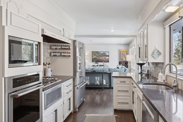 kitchen featuring appliances with stainless steel finishes, tasteful backsplash, white cabinetry, sink, and dark wood-type flooring