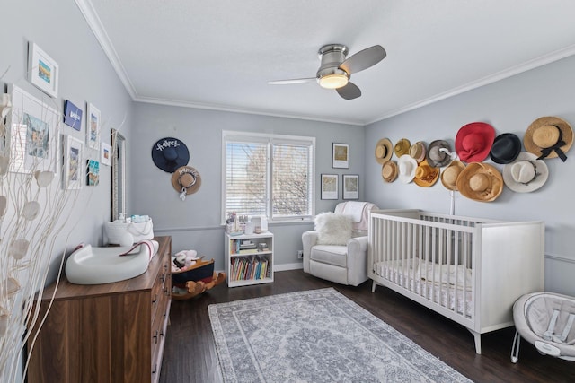 bedroom featuring crown molding, dark wood-type flooring, a nursery area, and ceiling fan