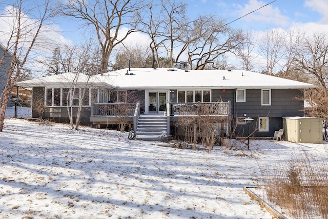 snow covered back of property featuring a deck