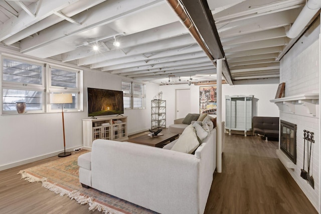 living room featuring hardwood / wood-style flooring, a fireplace, rail lighting, and a healthy amount of sunlight