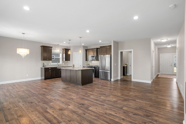 kitchen featuring decorative light fixtures, dark brown cabinets, dark hardwood / wood-style flooring, a kitchen island, and stainless steel appliances