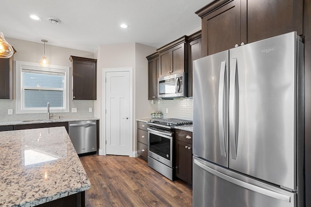 kitchen featuring sink, appliances with stainless steel finishes, light stone countertops, dark hardwood / wood-style flooring, and decorative light fixtures