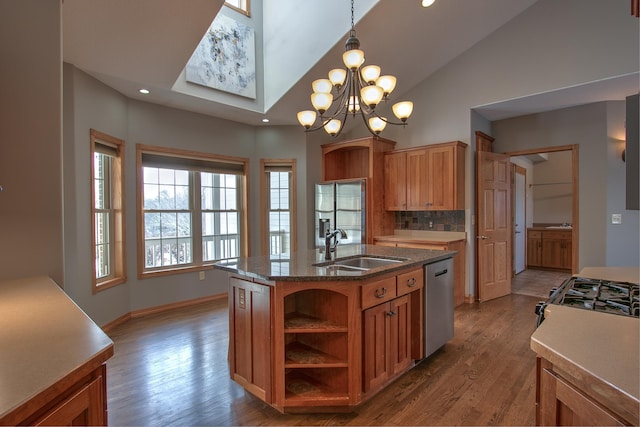 kitchen featuring decorative light fixtures, dishwasher, sink, hardwood / wood-style flooring, and a kitchen island with sink