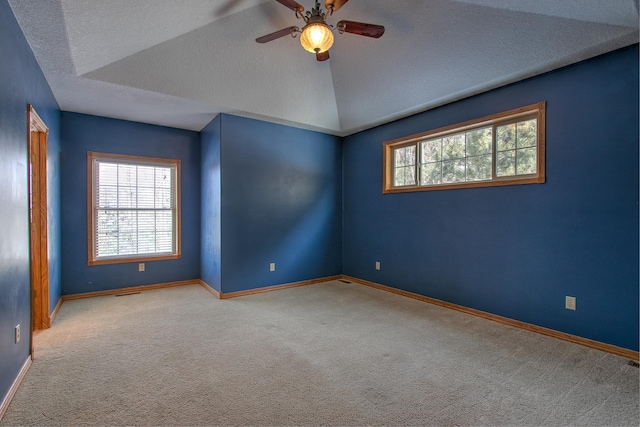 carpeted empty room with ceiling fan, lofted ceiling, and a textured ceiling