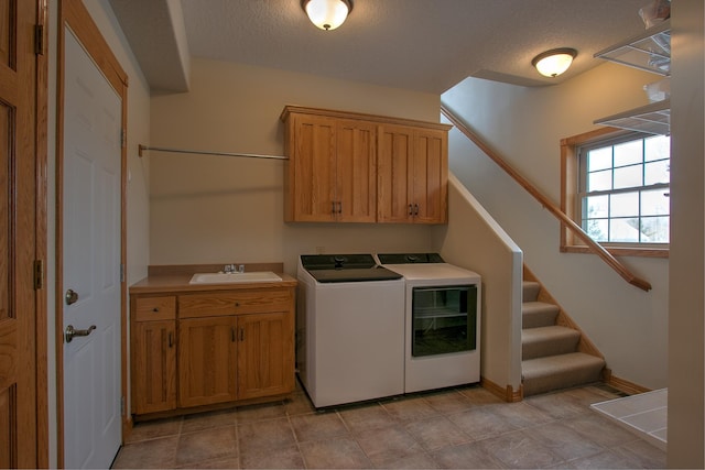 laundry room with cabinets, sink, a textured ceiling, and washer and clothes dryer