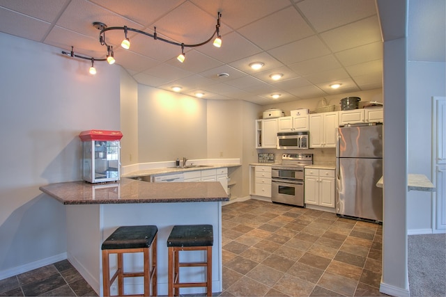 kitchen with appliances with stainless steel finishes, sink, a breakfast bar area, white cabinets, and kitchen peninsula