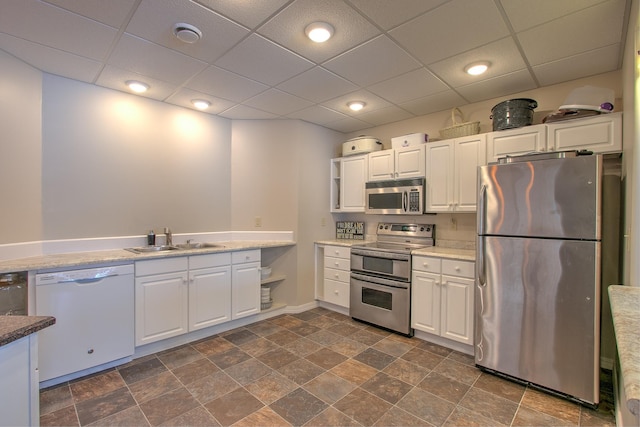 kitchen featuring white cabinetry, sink, stainless steel appliances, and a drop ceiling