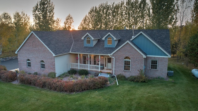 view of front of home featuring cooling unit, a lawn, and a porch