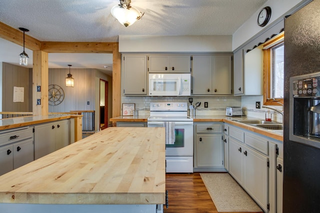 kitchen featuring butcher block countertops, sink, white appliances, and decorative light fixtures